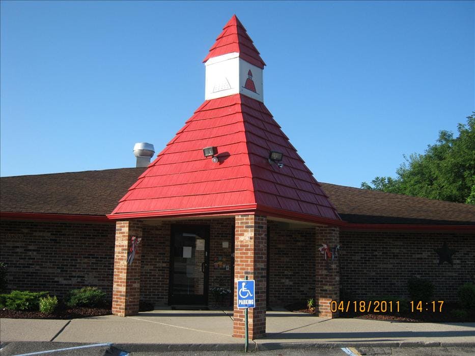 Brick building with a steep red roof and a small white steeple