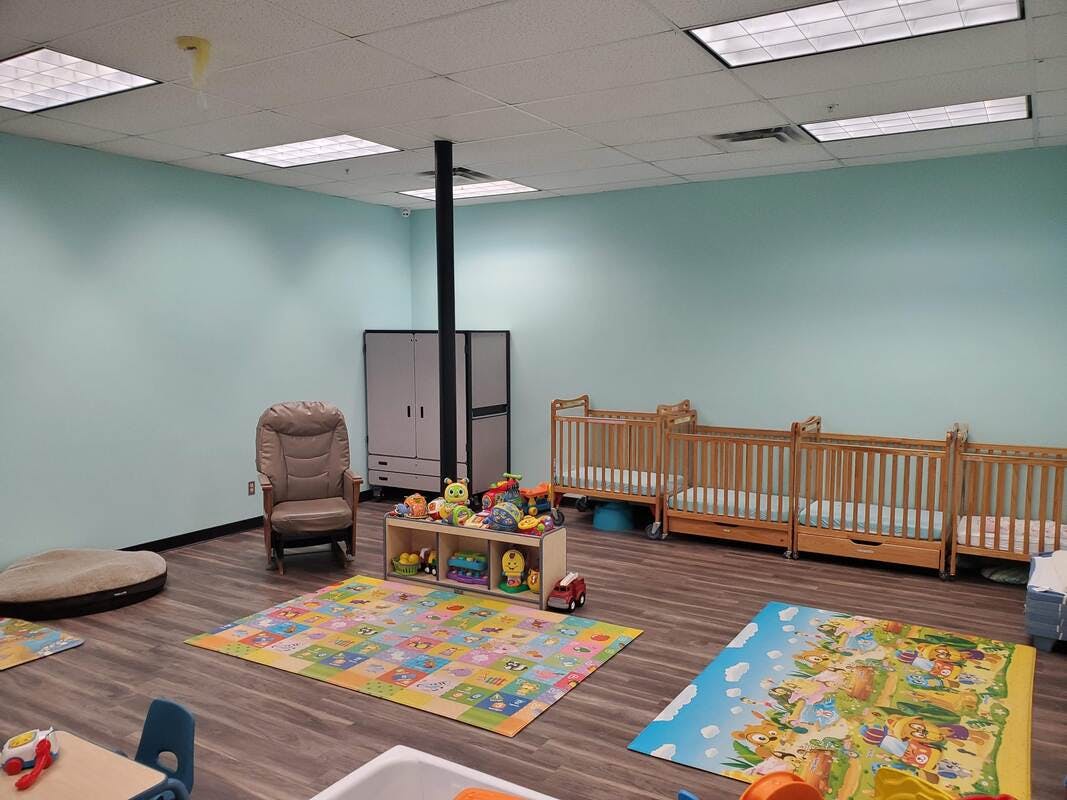 Nursery room with cribs, play mats, and toys