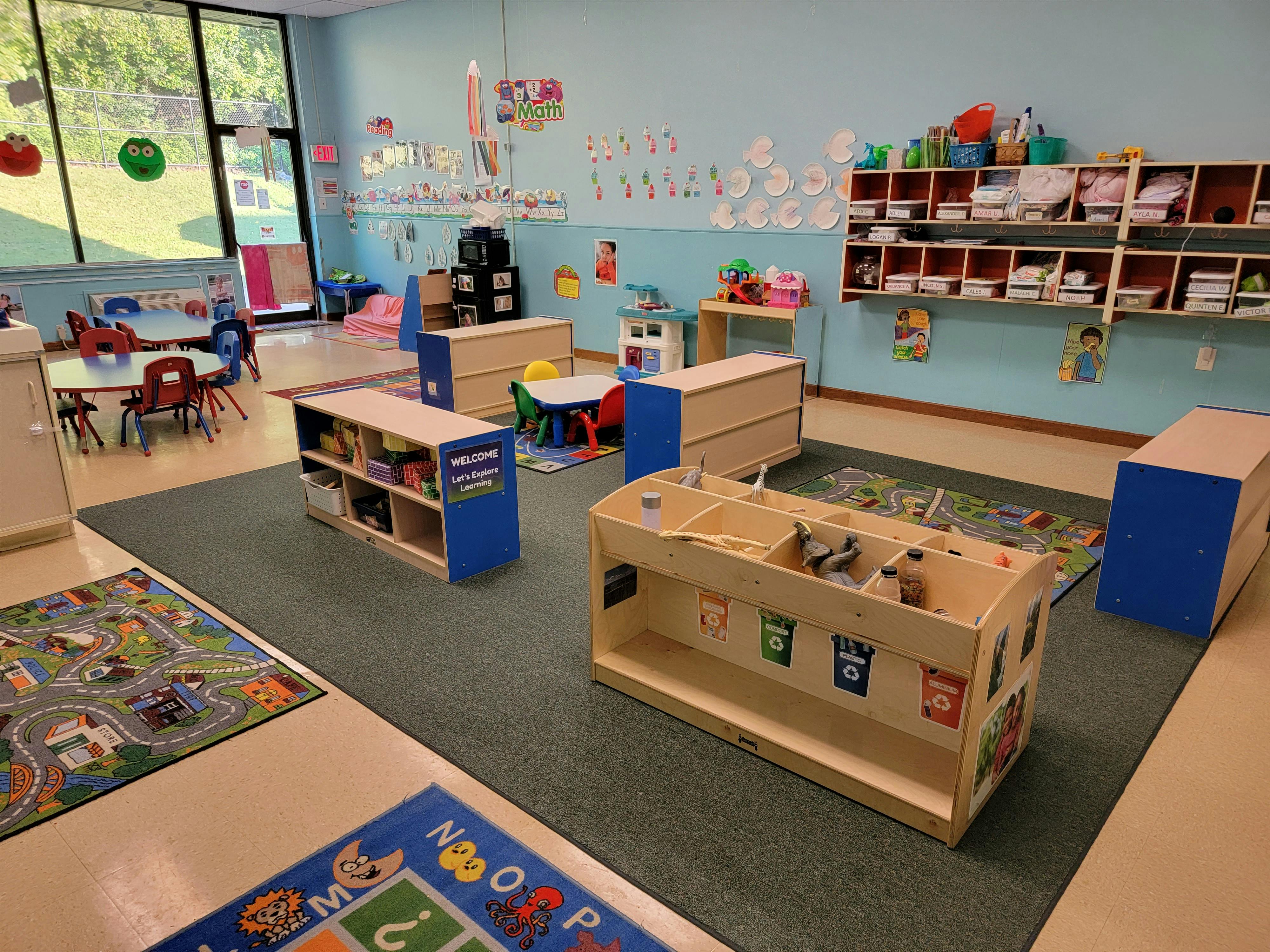 Classroom with tables, chairs, shelving units, and rugs