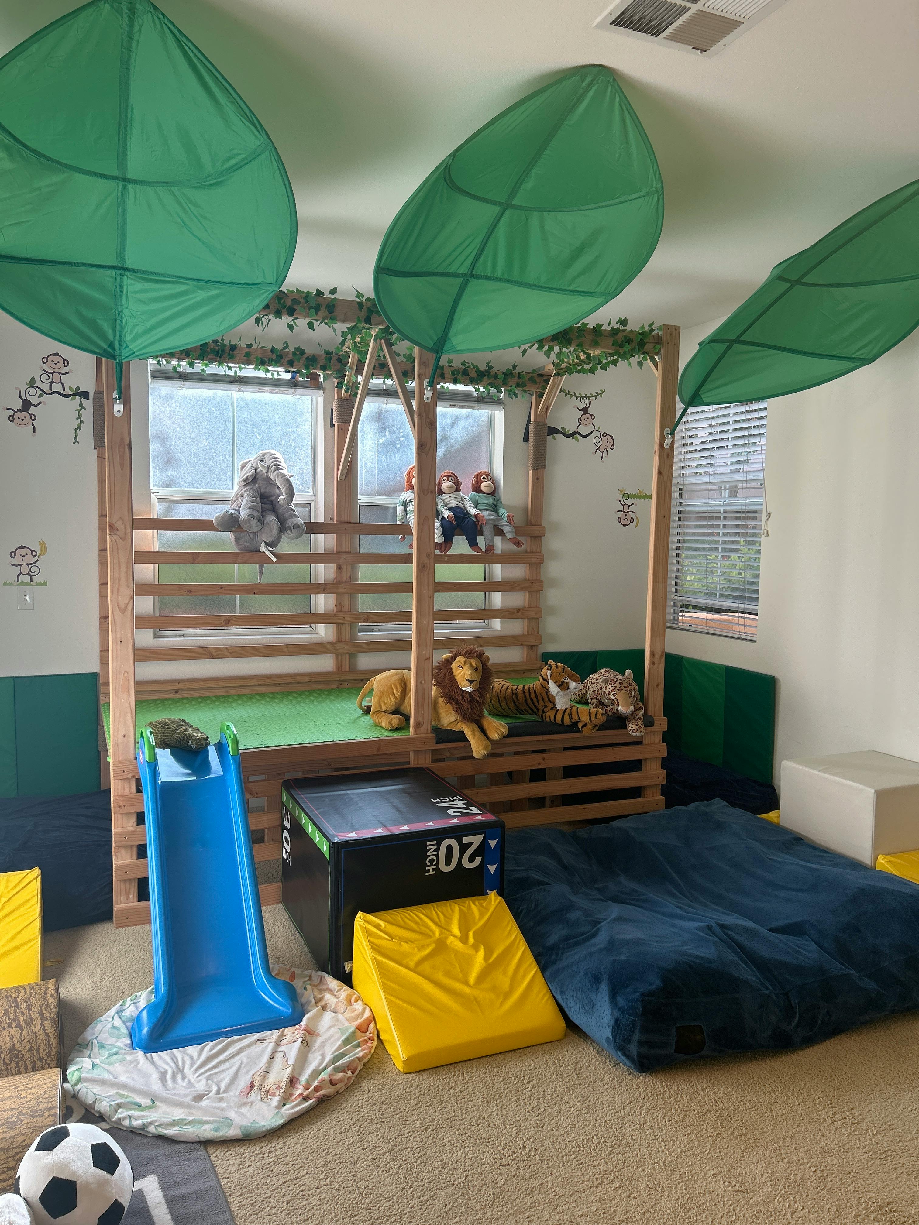 Indoor play area with a wooden structure, slide, and stuffed animals
