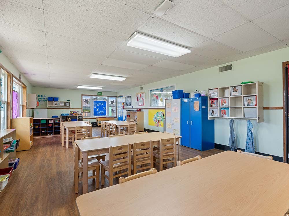 Empty classroom with small wooden tables and chairs