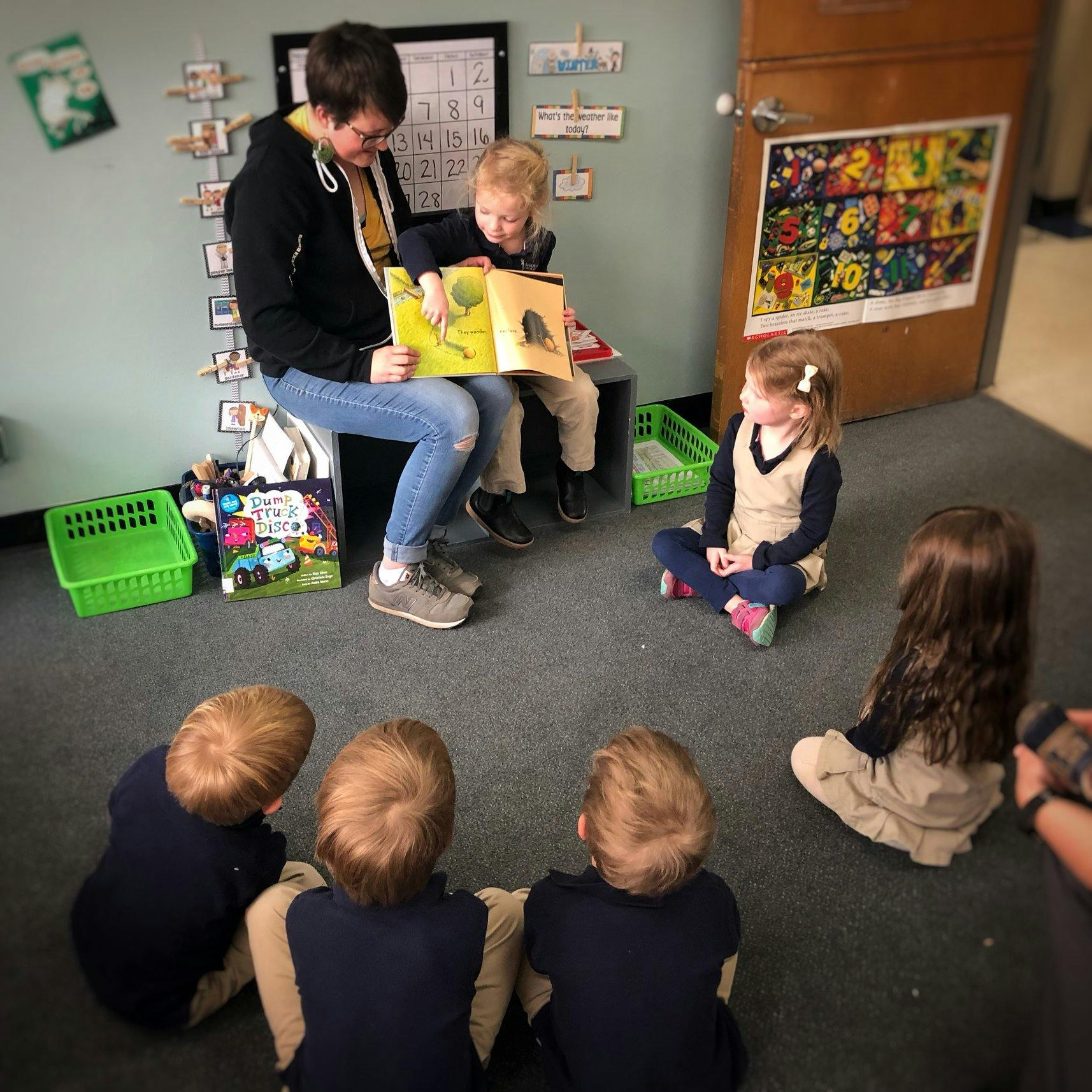 Person reading a book to children in a classroom