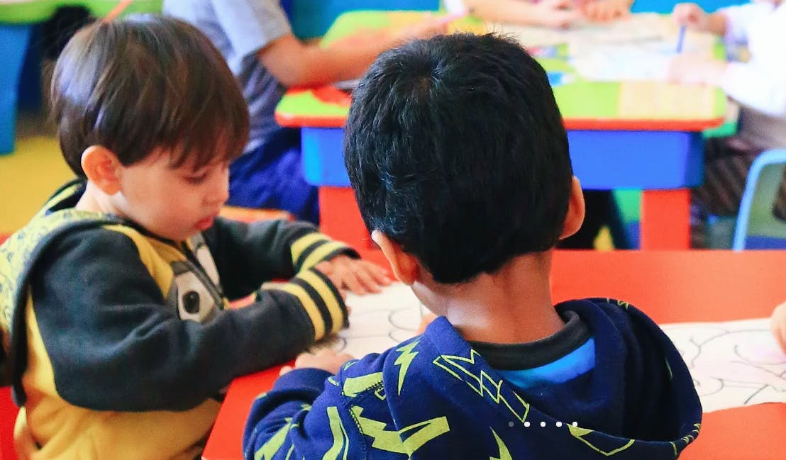 Two children at a table looking at papers