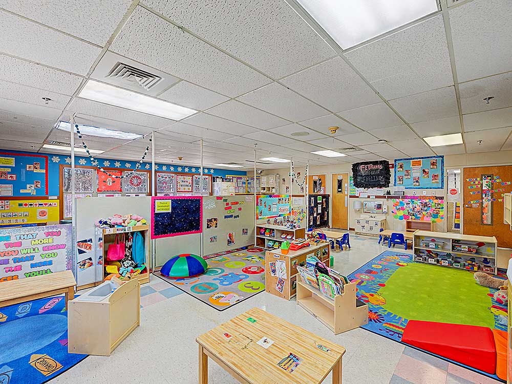 Empty children's classroom with colorful rugs and learning materials