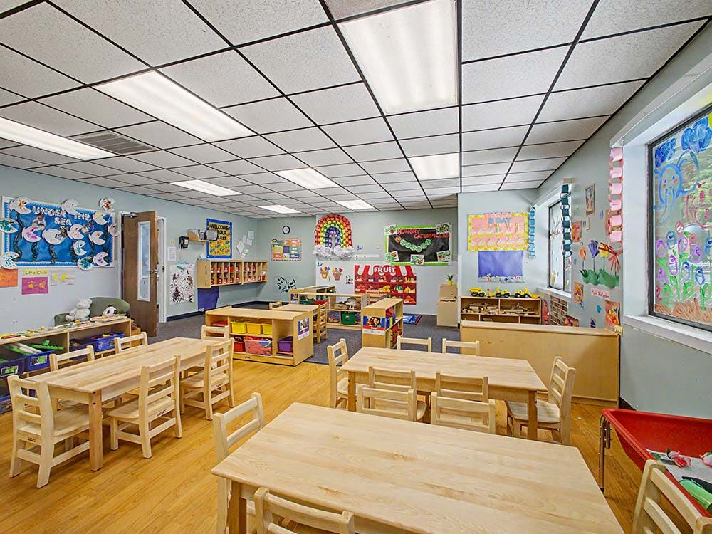 Empty classroom with small wooden tables and chairs, decorated walls
