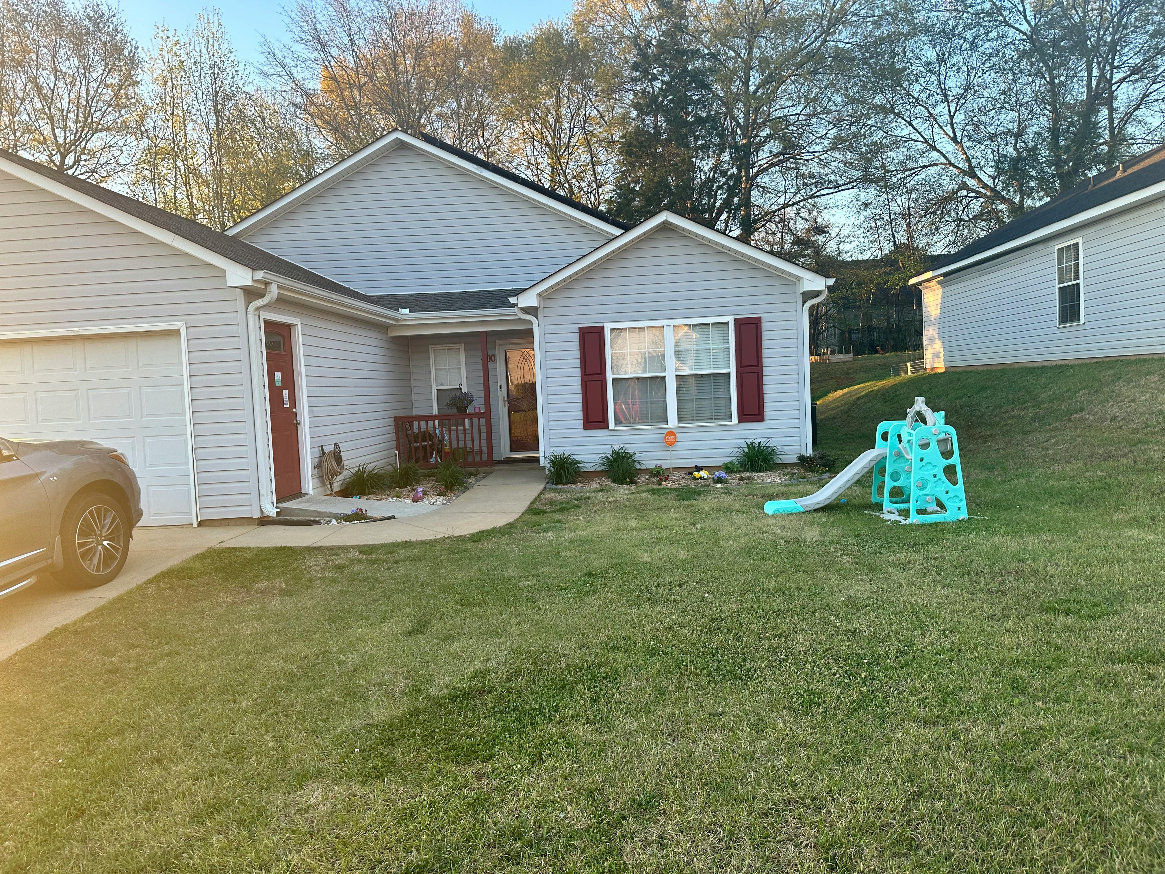 House with a car in the driveway and a small slide in the yard
