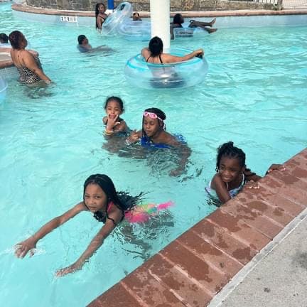 Several people swimming in a pool, including children and adults