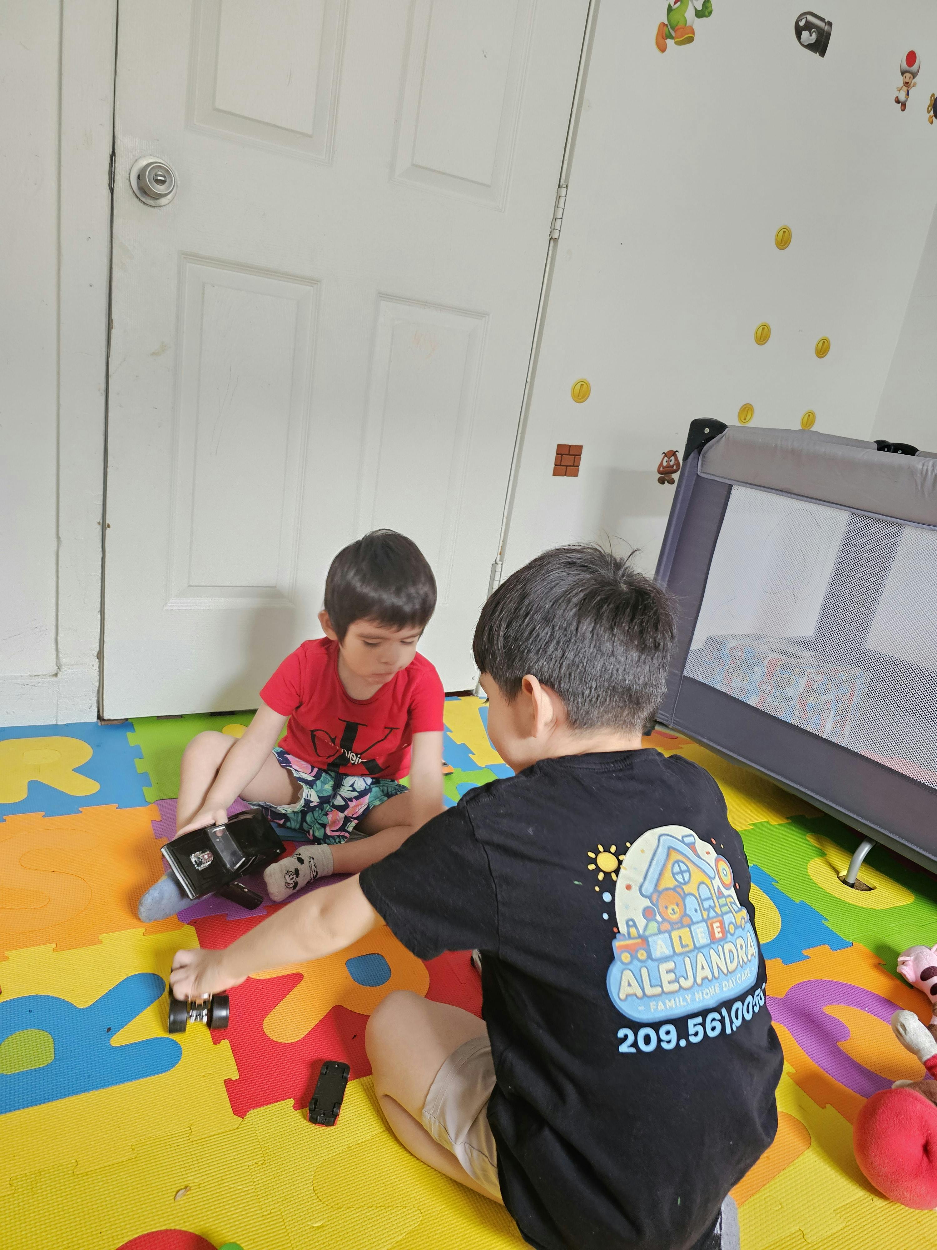 Two children playing with toy cars on a colorful playmat
