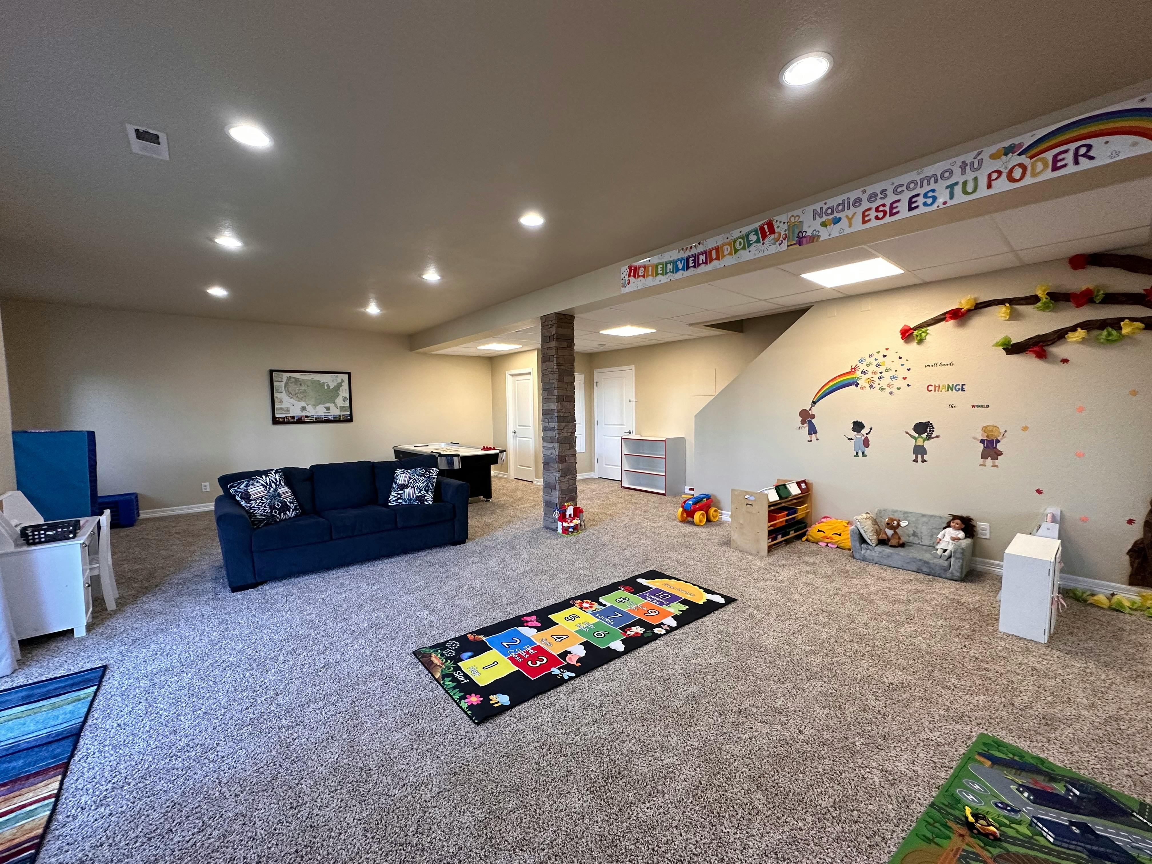 Large room with a sofa, play mat, and wall decorations