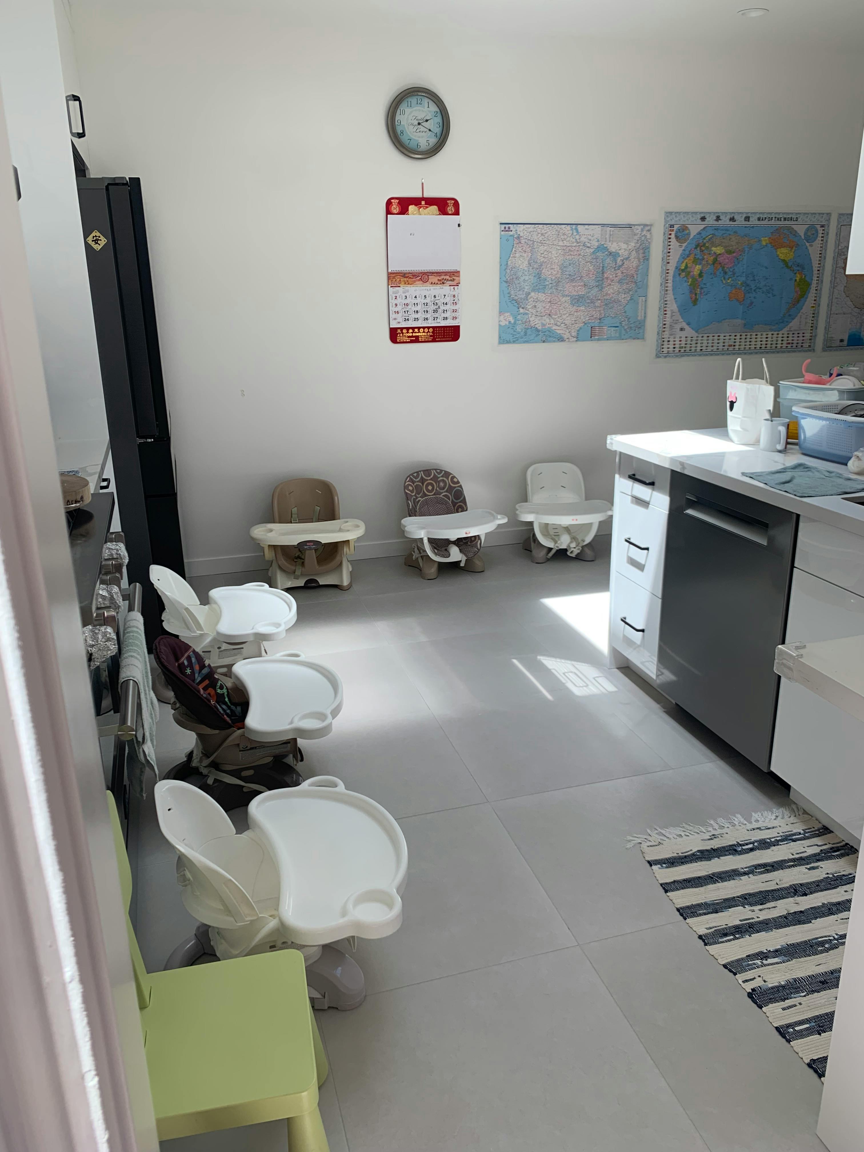 Multiple high chairs in a room with a calendar and maps on the wall