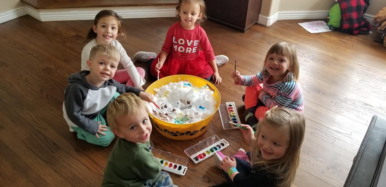 Children sitting around a large bowl of white material with small items