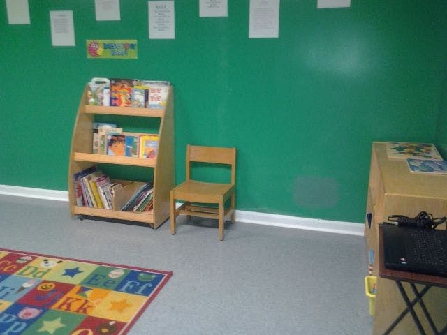 Bookshelf with books, small chair, and colorful rug in a classroom
