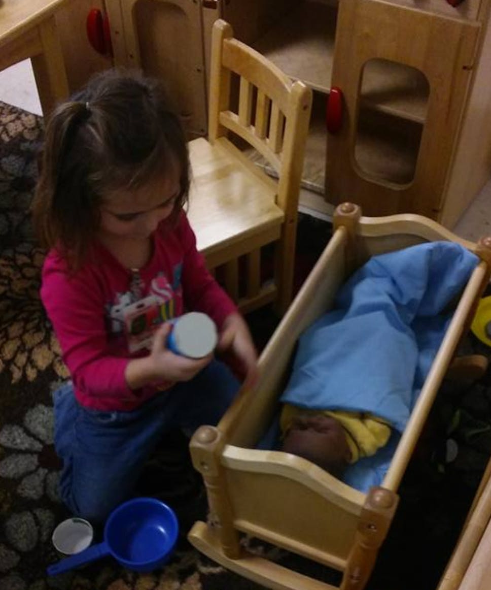 Child playing with a doll in a wooden cradle