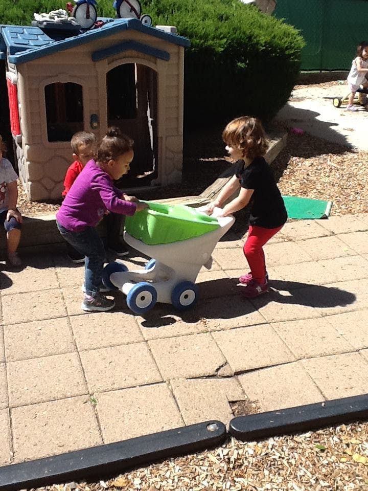 Two children playing with a toy wagon outdoors