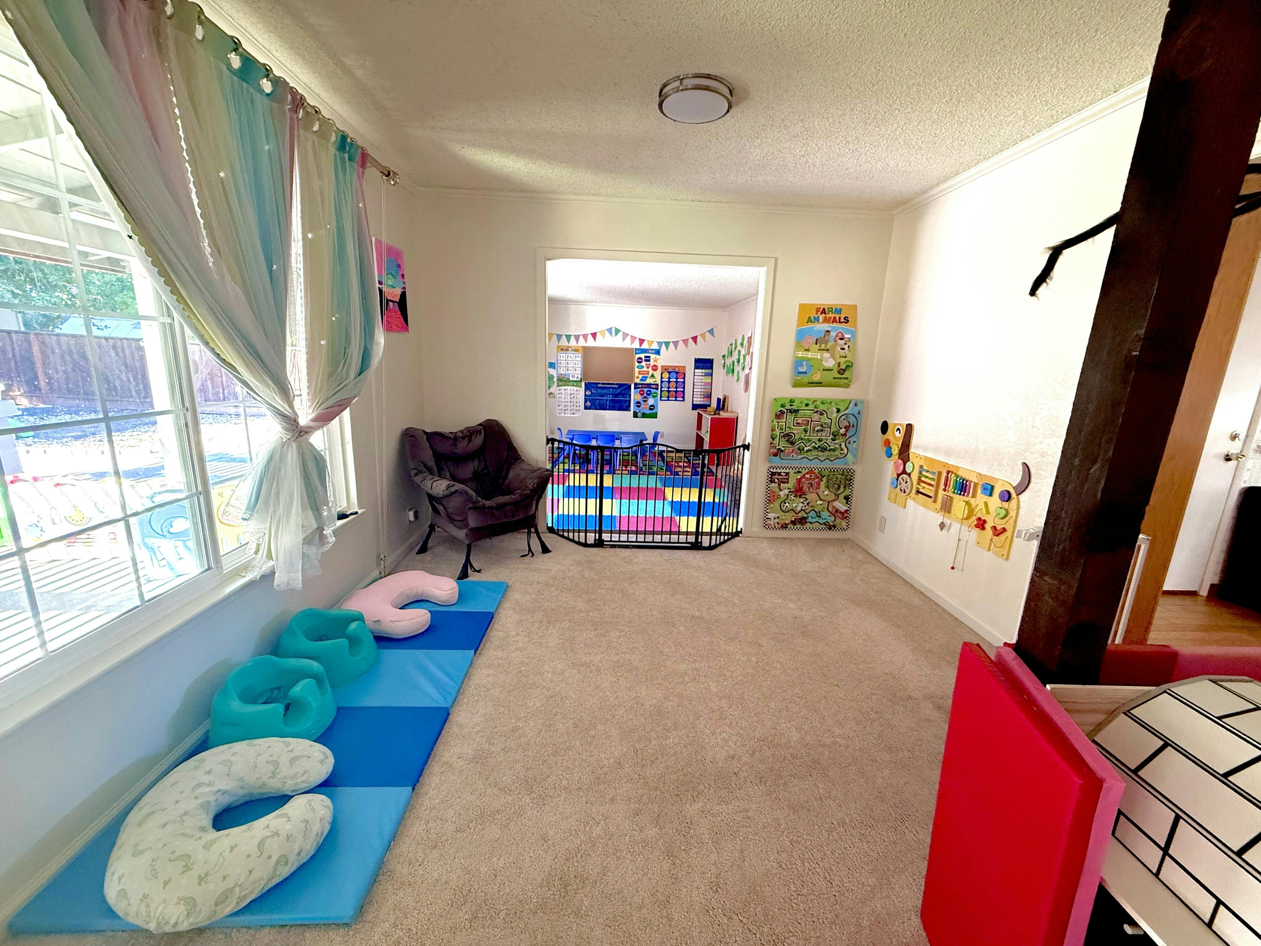 Playroom with baby floor seats on mats and a child activity wall