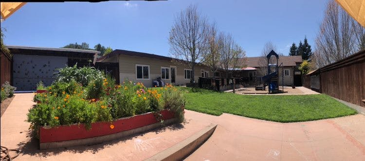 House exterior with garden bed, lawn, and playground