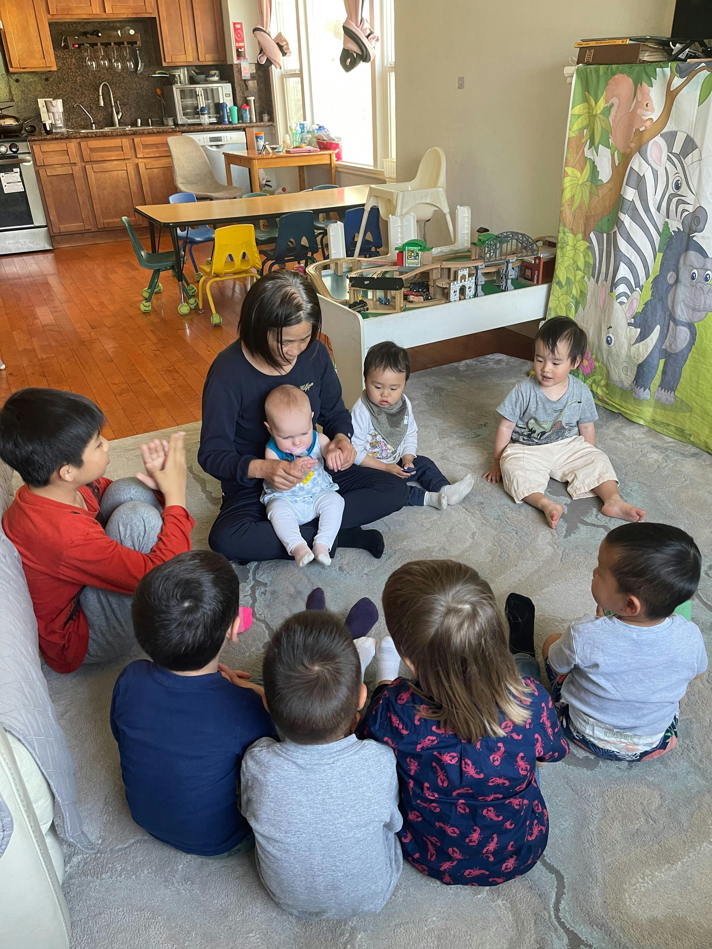 Adult and group of children sitting on the floor in a room