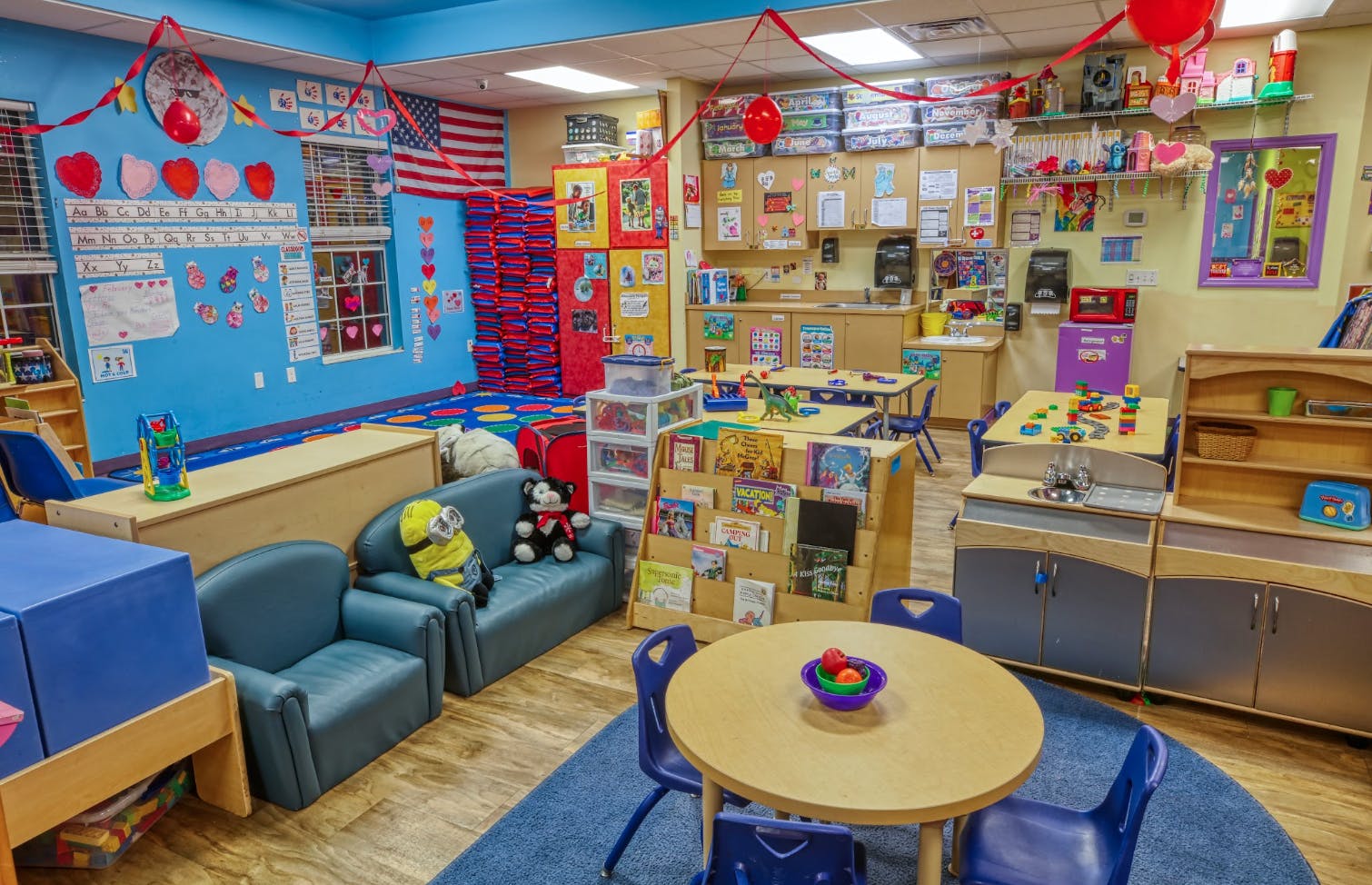 Colorful classroom with child-sized furniture, play kitchens, and learning materials