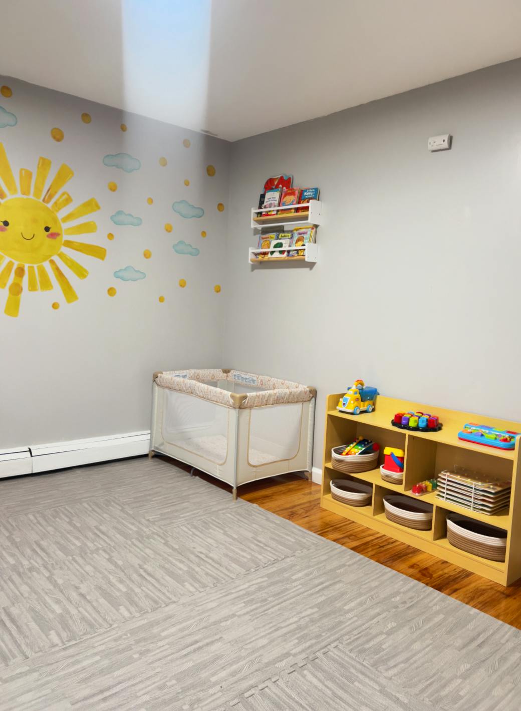 Nursery room with a crib, toy shelf, and sun wall decal