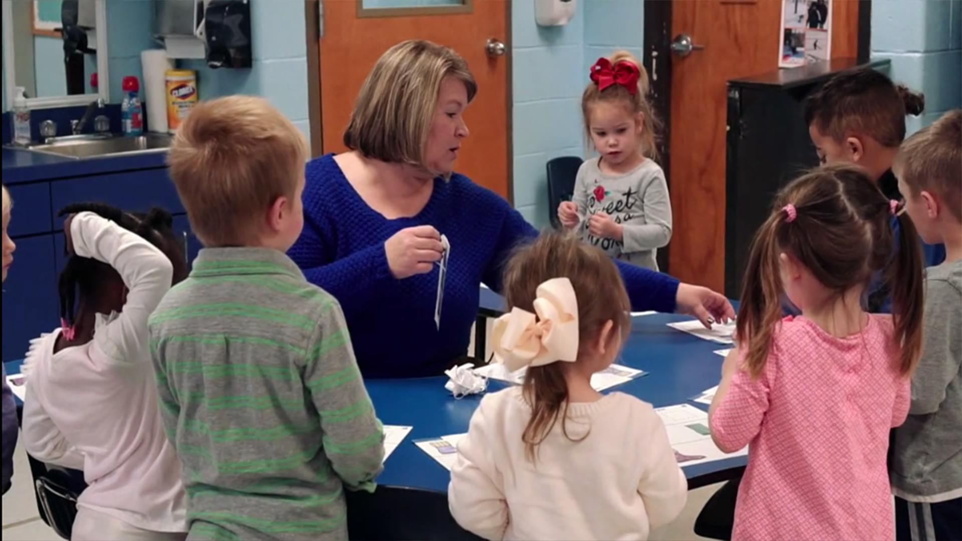 Adult and children gathered around a table in a classroom