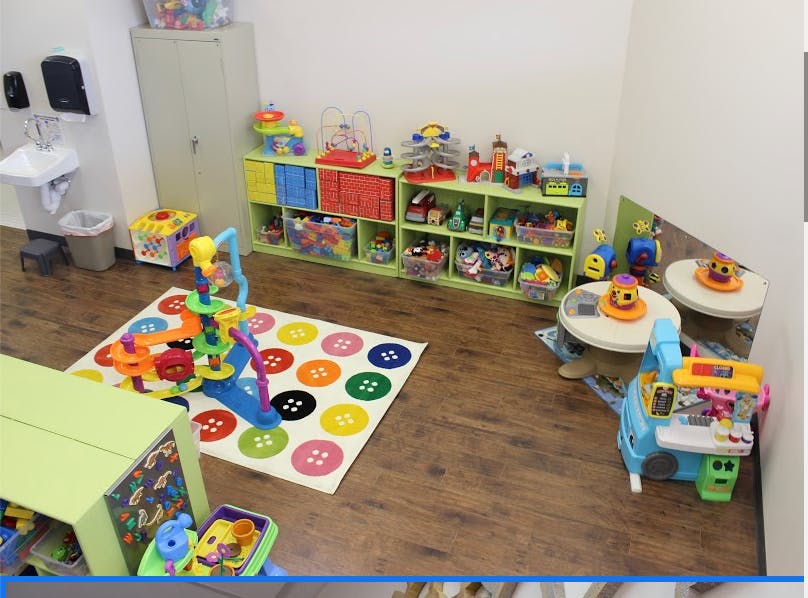 Playroom with toys, shelves, tables, and a button-patterned rug
