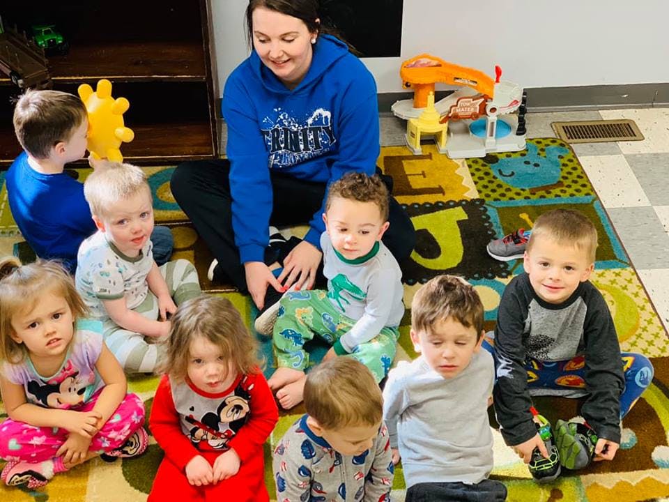 Adult sitting on floor with several young children around them