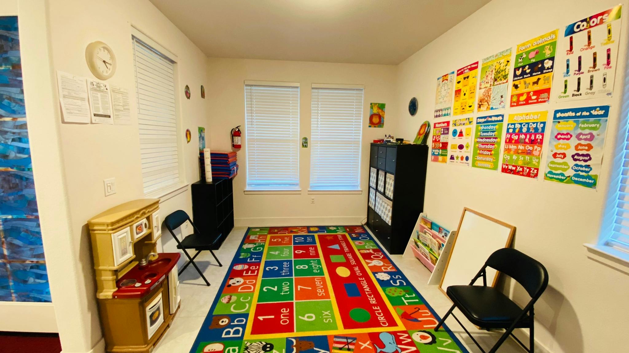 Classroom with colorful alphabet rug, educational posters, and play kitchen