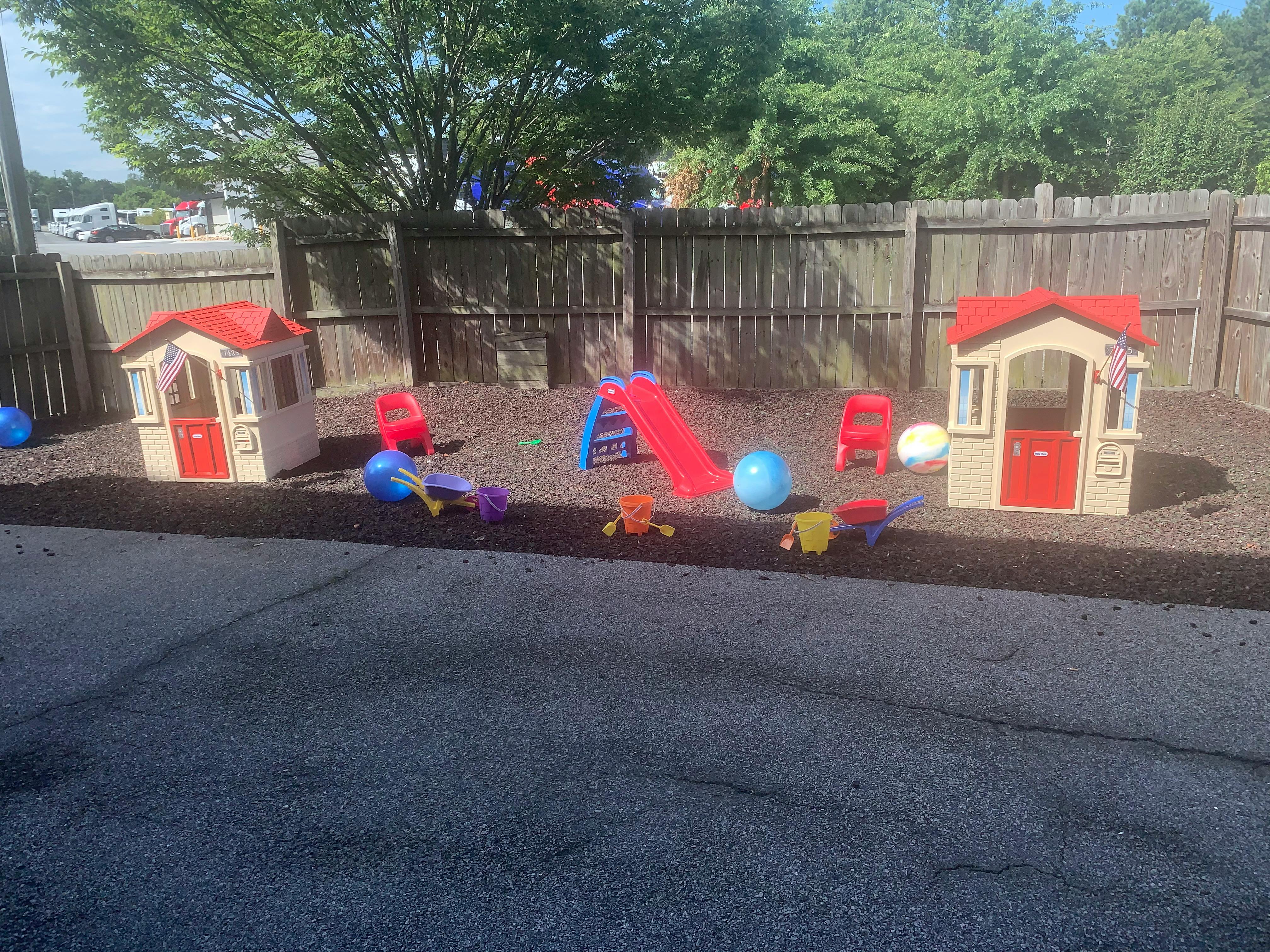 Outdoor play area with two playhouses, a slide, and various toys