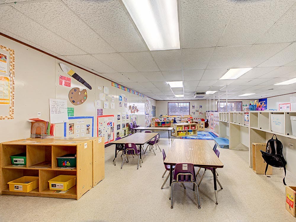 Empty classroom with tables, chairs, and cubbies