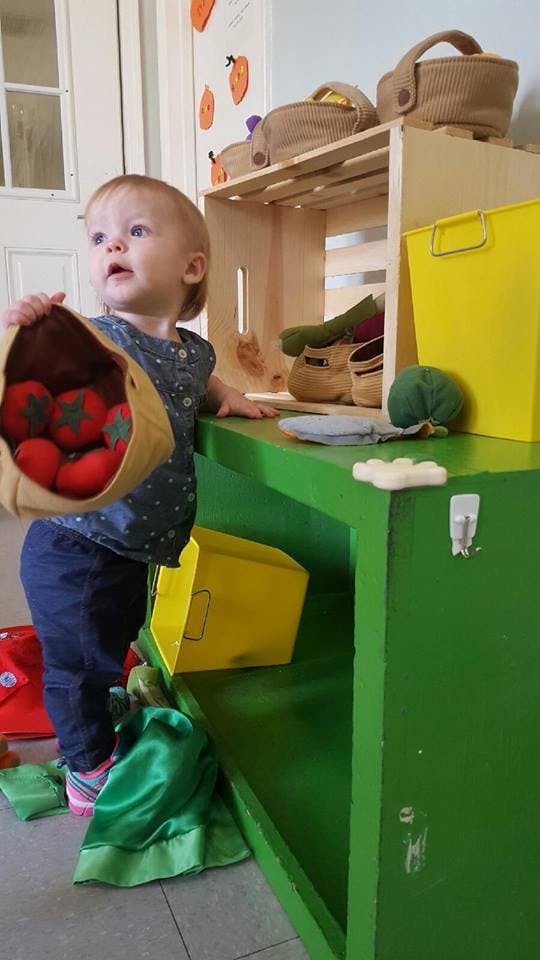 Child holding a bag of toy tomatoes