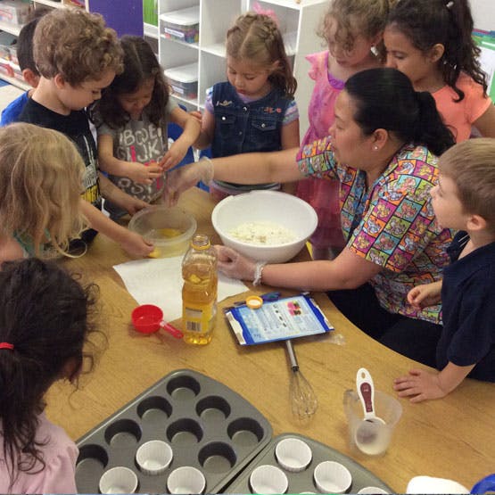 Adult and children gathered around a table mixing ingredients