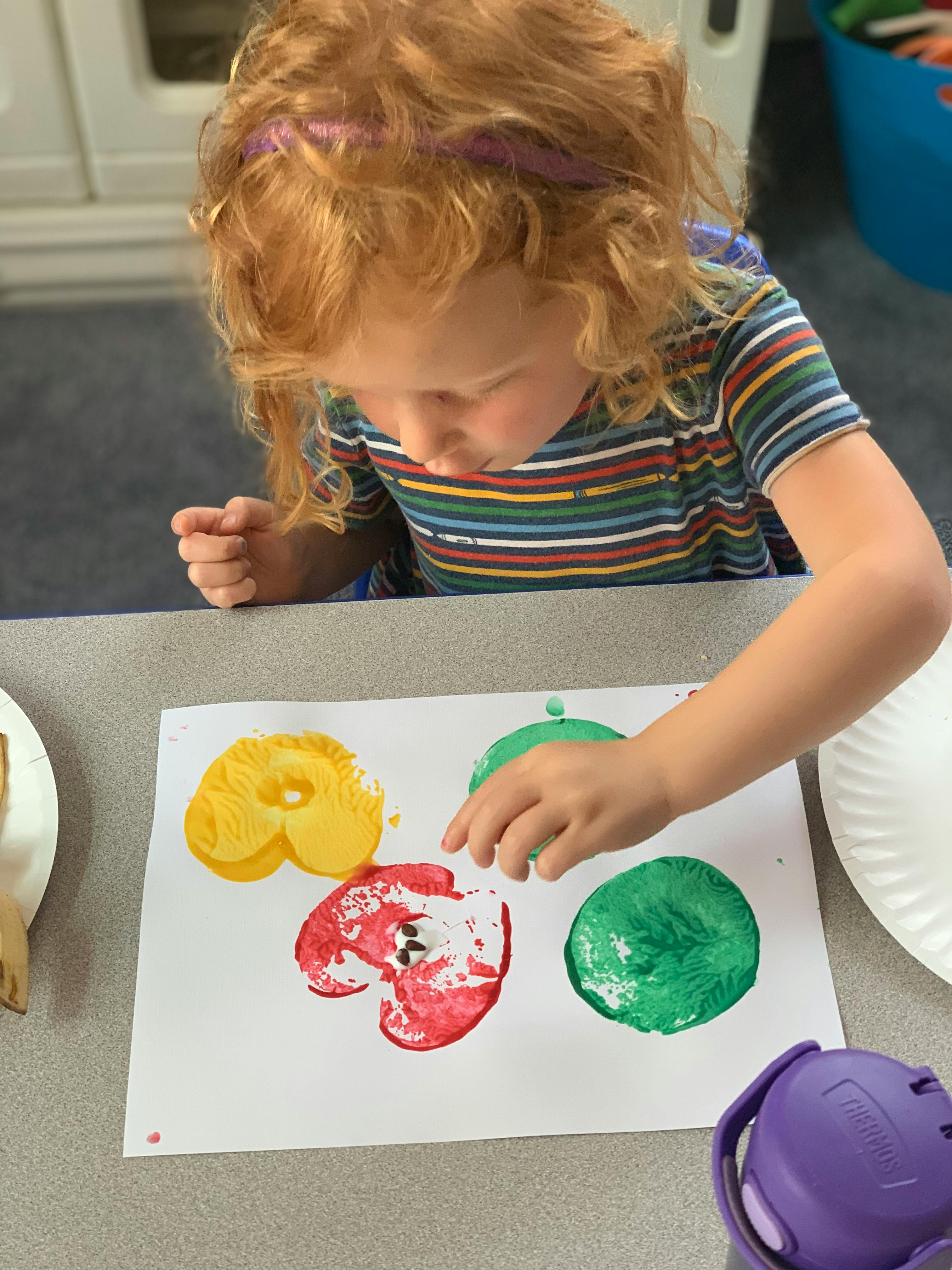 Child making apple prints with paint
