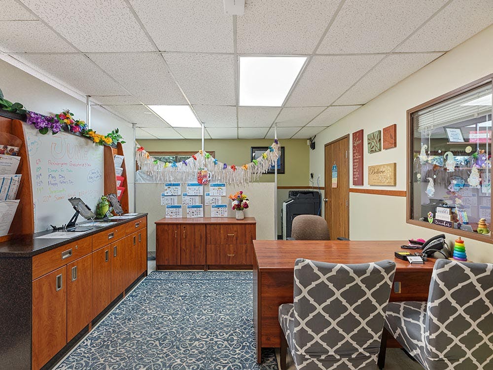 Reception area or office with a desk, chairs, and a whiteboard displaying 'June' dates