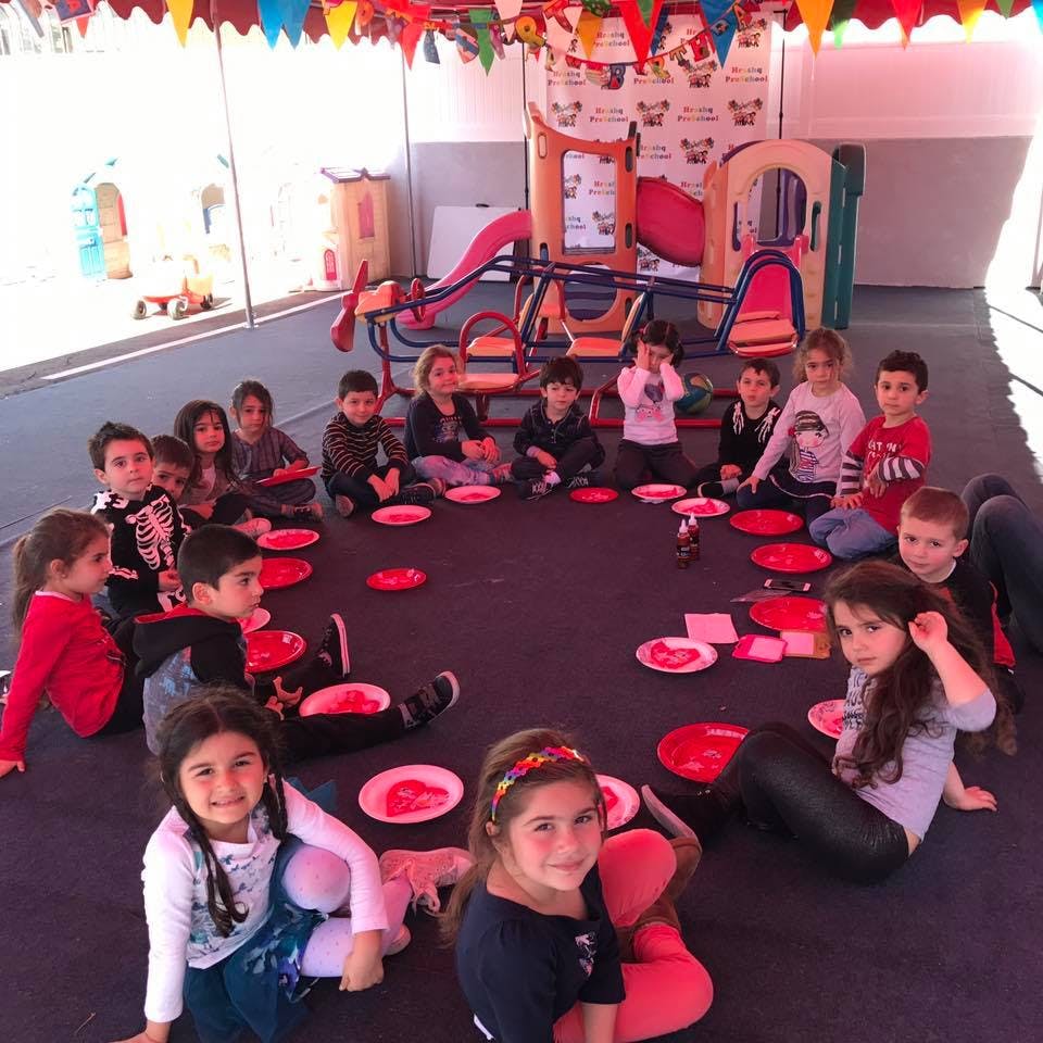 Children sitting in a circle on the floor with plates in front of them