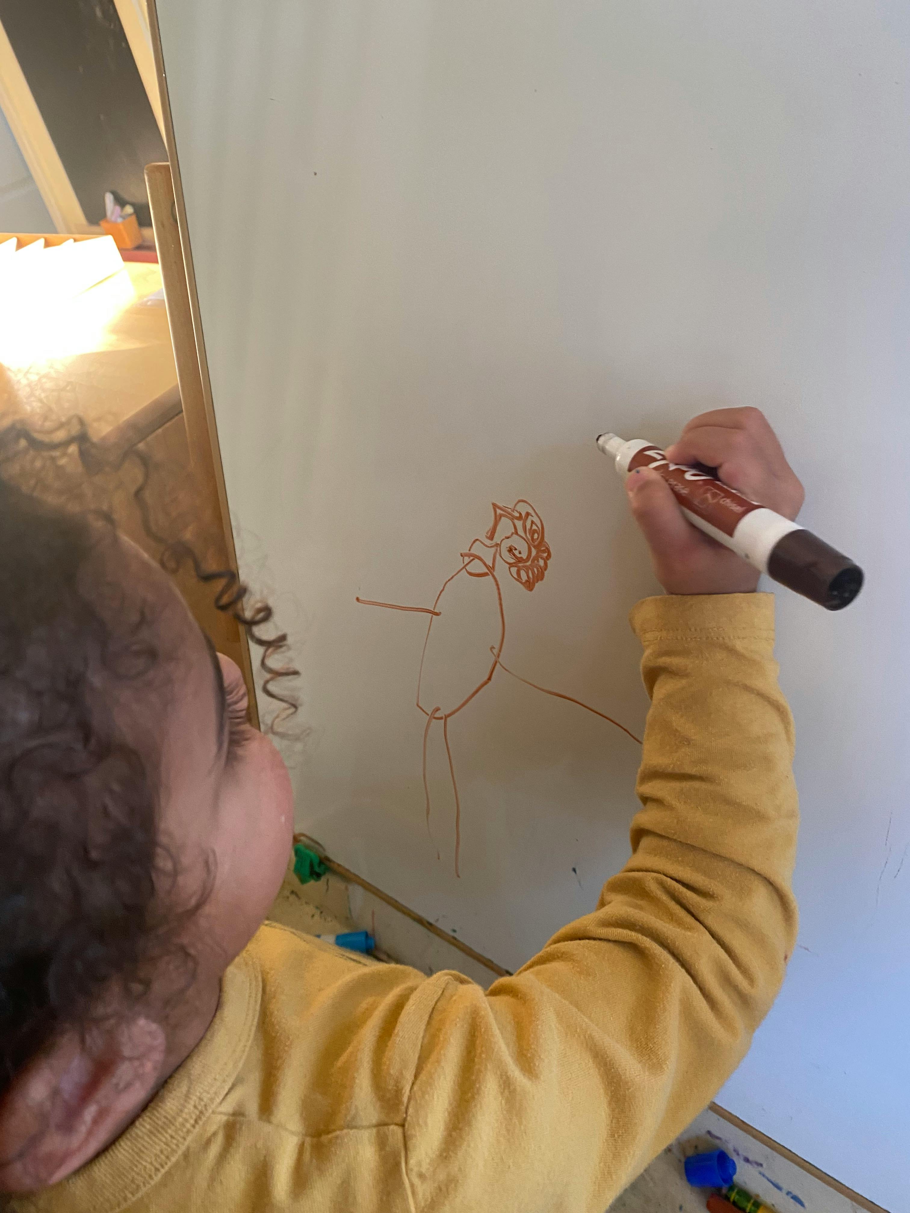 Child drawing on a whiteboard with a marker