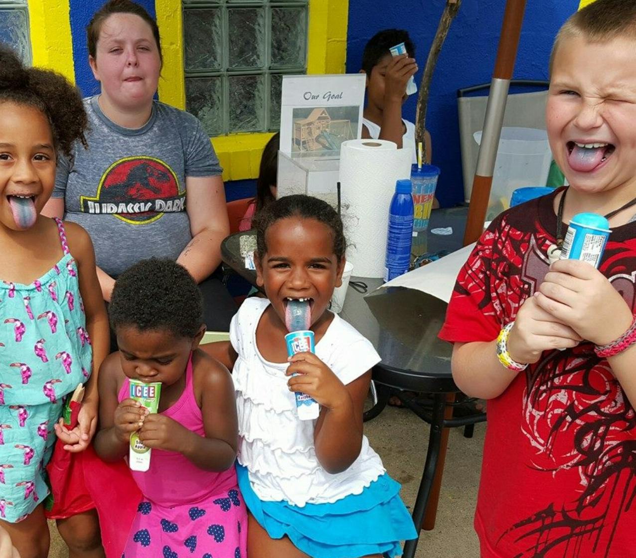 Children eating frozen treats with a person in the background