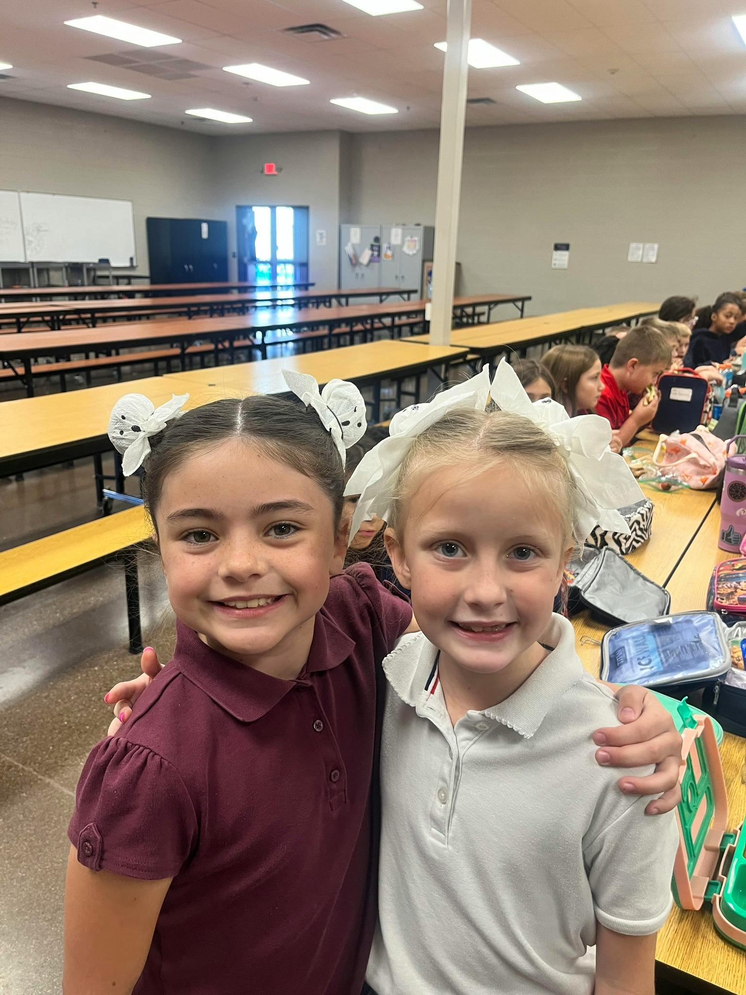 Two children with arms around each other in a cafeteria