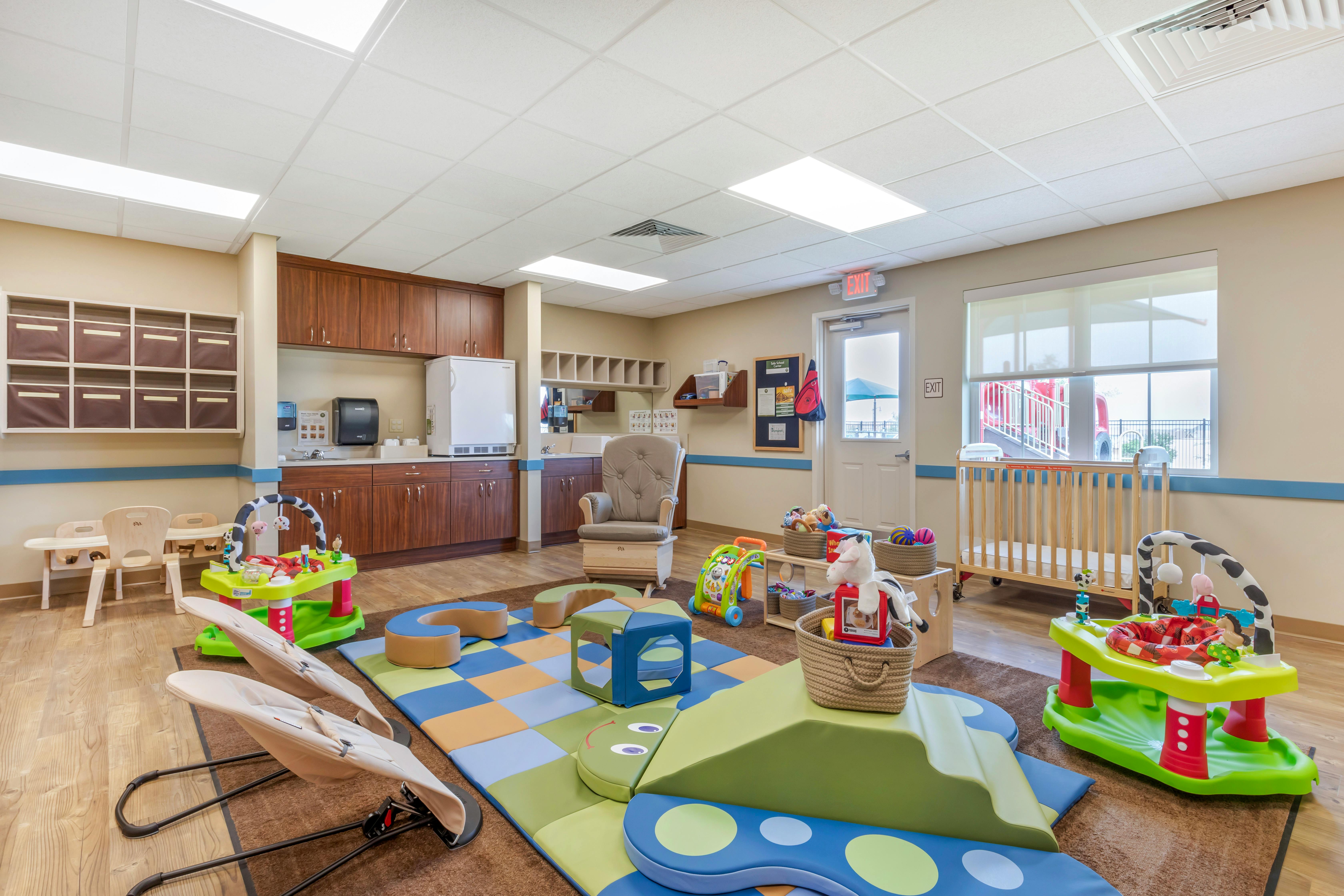 Baby and toddler play area with crib, soft play structures, and rocking chair