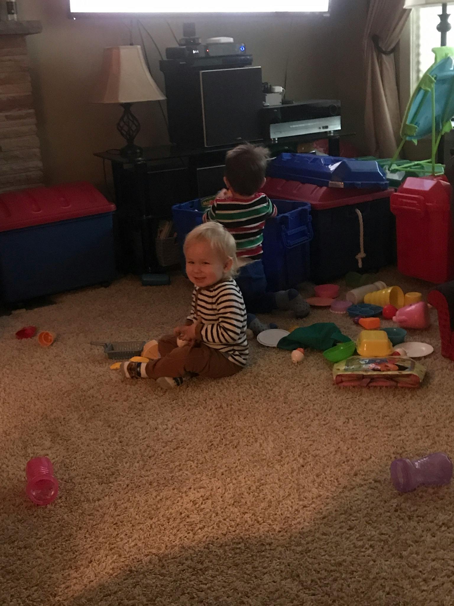 Two children playing on a carpeted floor with toys