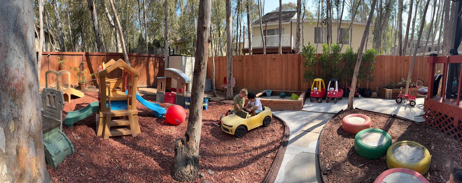 Children playing with toy vehicles in a backyard playground