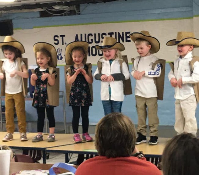 Children in cowboy hats and vests on a stage with "ST. AUGUSTINE" sign