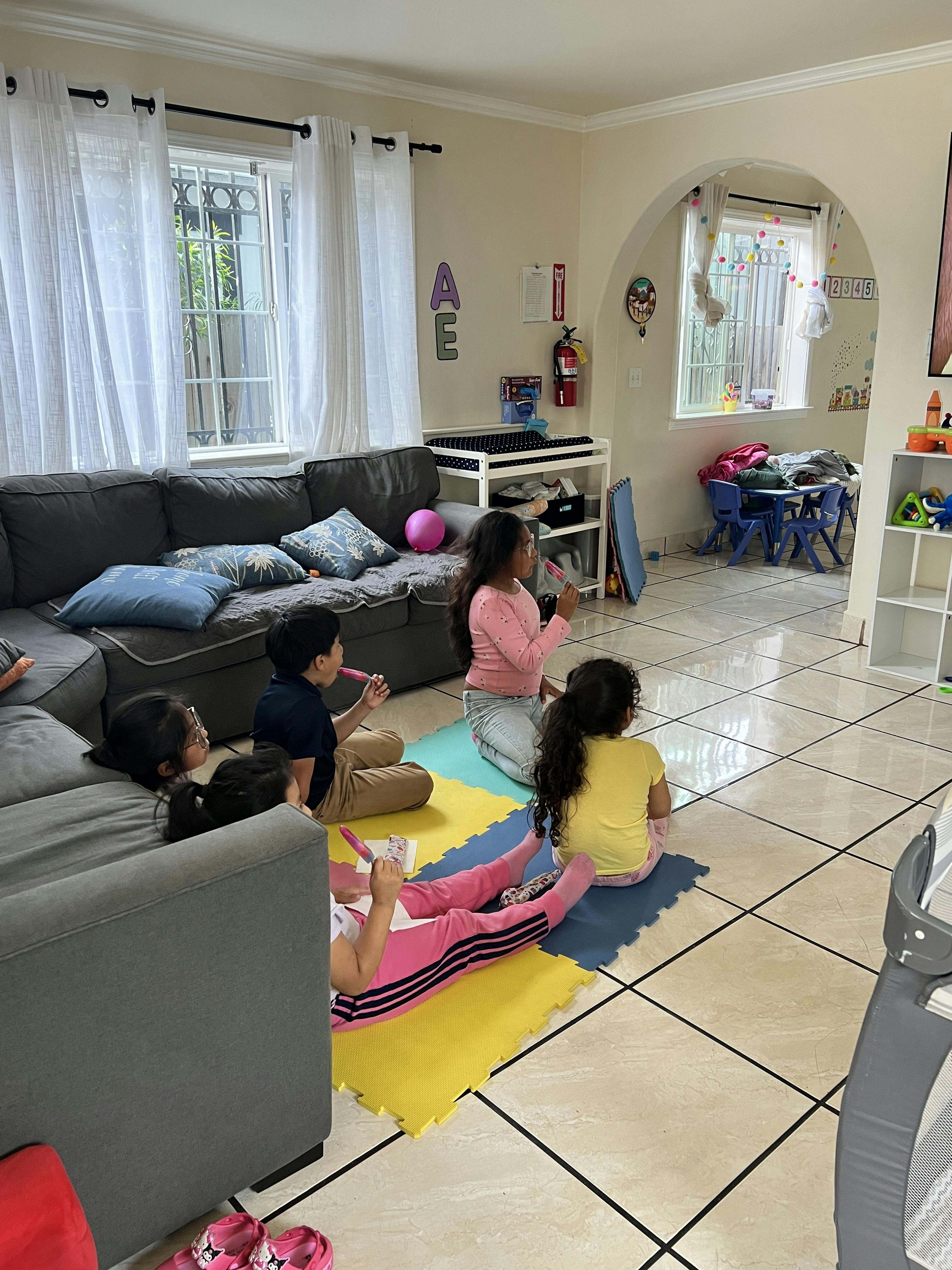Group of children sitting on play mats in a living room