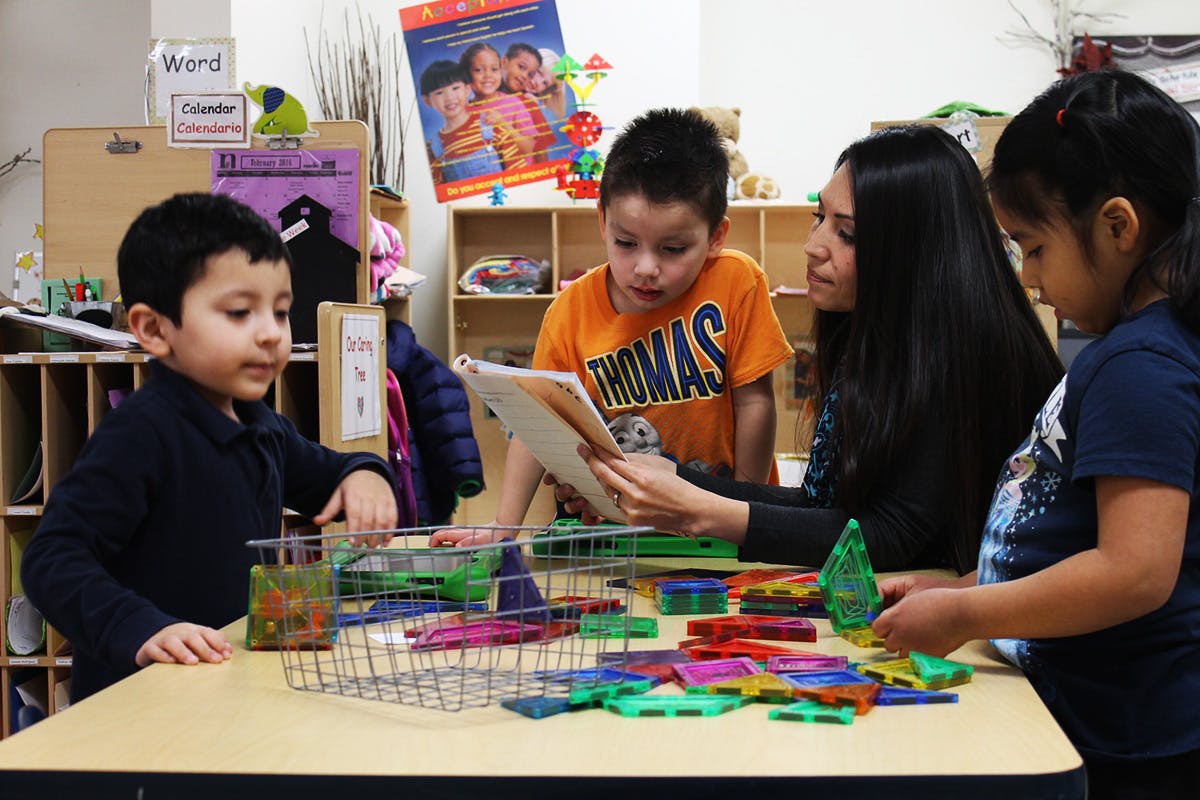Adult and three children looking at a tablet in a classroom