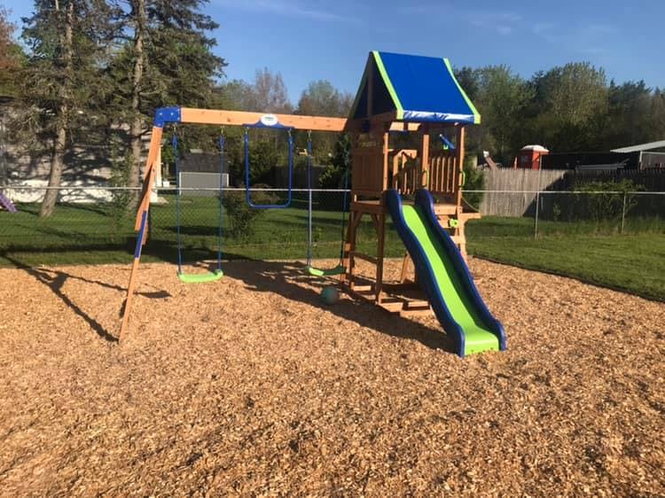 Playset with swings and a slide on wood chips