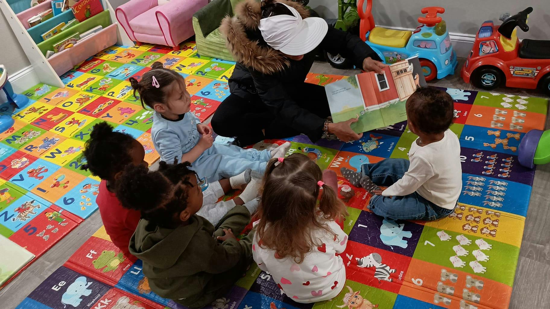 Person reading a book to multiple children in a playroom