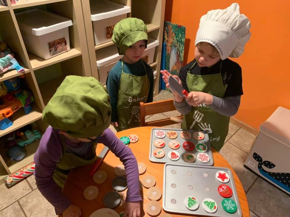 Three children decorating cookies at a table