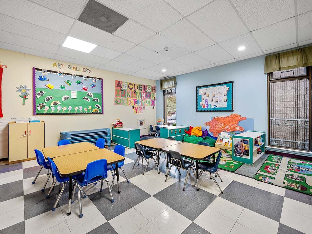 An empty children's classroom with tables, chairs, and decorations
