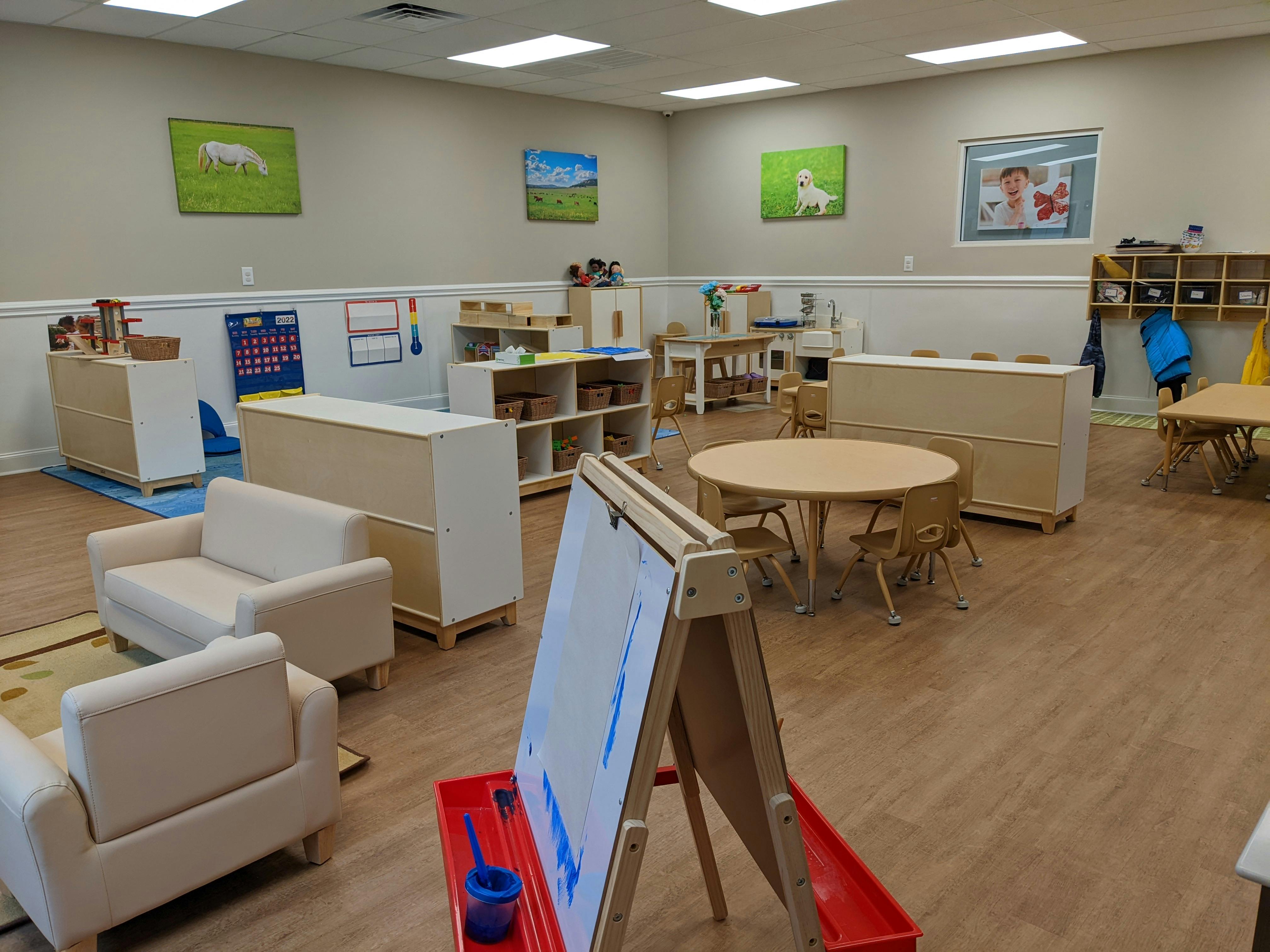 Empty classroom with small tables, chairs, and an easel