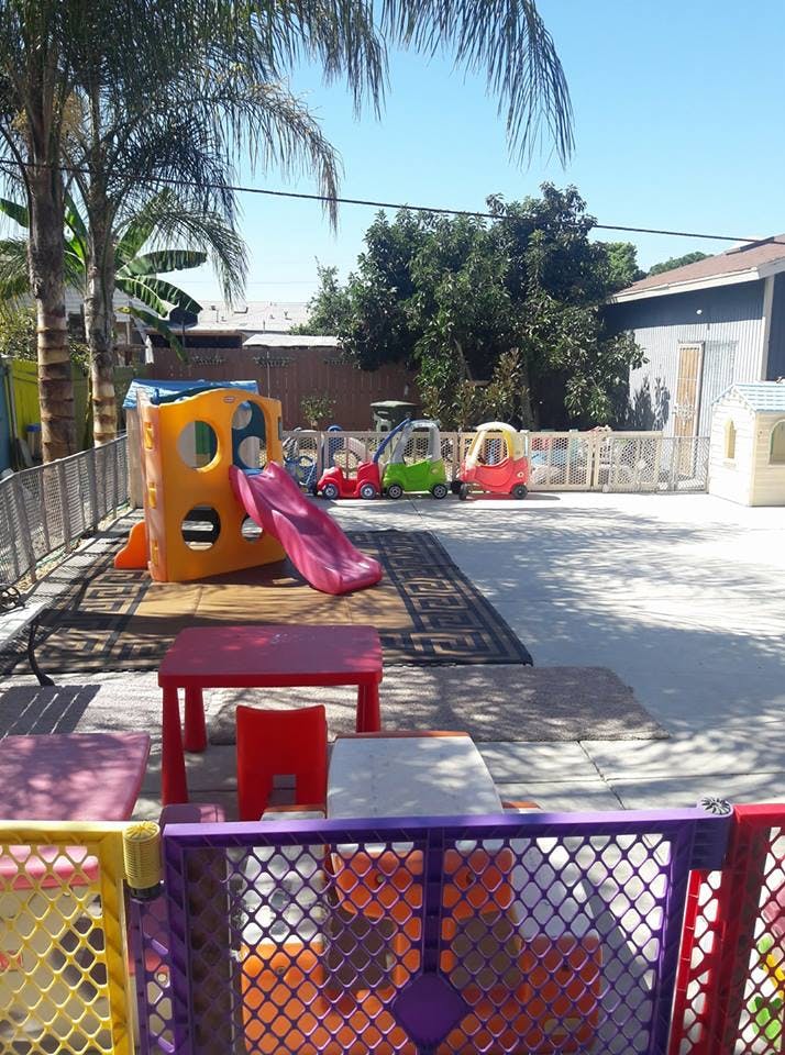 Outdoor play area with a slide, small cars, and tables