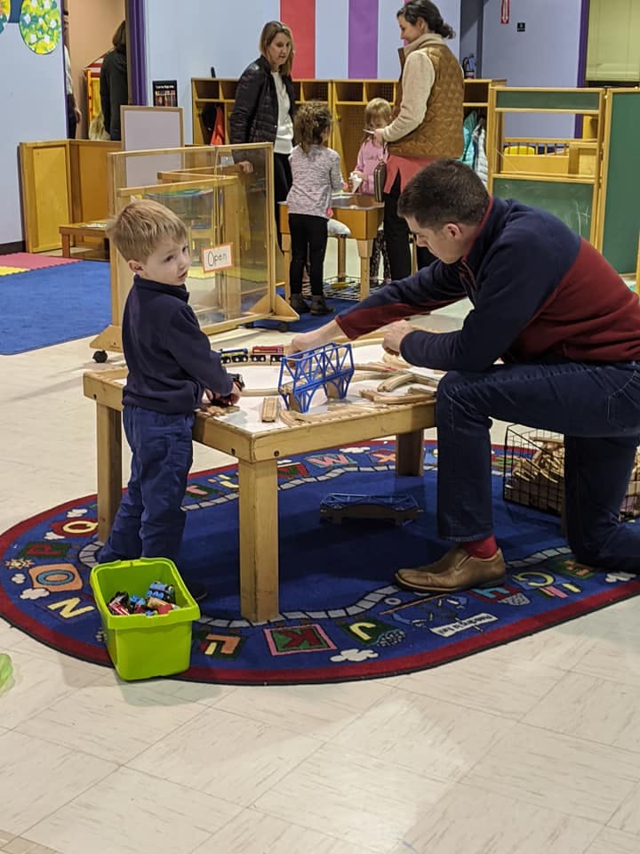 Adult and child playing with toy trains on a table
